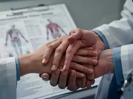Eine Nahaufnahme der Hand eines Patienten auf der Hand eines Arztes, mit einem unscharfen medizinischen Diagramm im Hintergrund. - Foto: über boerse-global.de