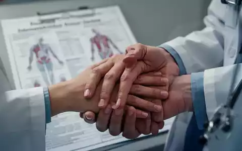 Eine Nahaufnahme der Hand eines Patienten auf der Hand eines Arztes, mit einem unscharfen medizinischen Diagramm im Hintergrund. - Foto: über boerse-global.de
