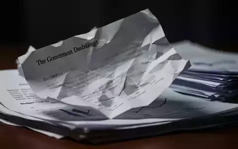 Ein zerknülltes oder gefaltetes Regierungsdokument, das geheime Sparmaßnahmen und Kürzungen symbolisiert, mit diffusem Hintergrund. - Foto: über boerse-global.de