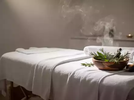 Ein ruhiger Massageraum mit sanftem Licht, einem bezogenen Massagetisch und aufsteigendem Dampf von Kräutern. - Foto: über boerse-global.de