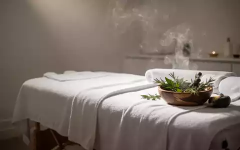 Ein ruhiger Massageraum mit sanftem Licht, einem bezogenen Massagetisch und aufsteigendem Dampf von Kräutern. - Foto: über boerse-global.de