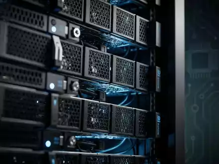 Nahaufnahme eines Server-Racks mit blauen Lichtern und einem Schaltplattendesign im Hintergrund, das KI und Halbleiter darstellt. - Foto: über boerse-global.de