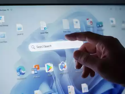 A hand interacts with a computer screen showing a Windows 11 search bar prioritizing local files and apps over web results. - Foto: über boerse-global.de