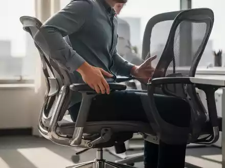 Ein moderner, ergonomischer Bürostuhl in einem hellen Büro, mit einer Person, die ihre Haltung anpasst. Fokus auf dynamisches Sitzen und Gesundheit. - Foto: über boerse-global.de