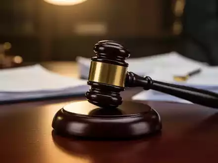 Ein Nahaufnahme eines Holzhammers auf einem dunklen Schreibtisch, umgeben von verschwommenen Rechtsdokumenten, die Arbeitsrecht symbolisieren. - Foto: über boerse-global.de