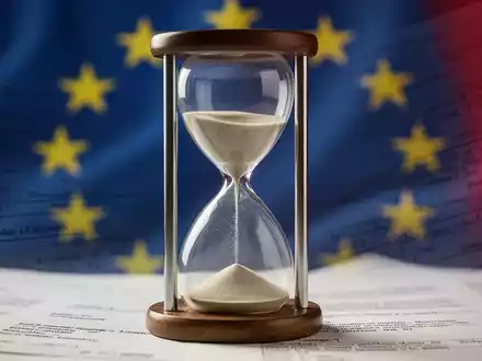 Eine stilisierte, leicht durchsichtige Sanduhr vor einem verschwommenen Hintergrund in EU-Flaggenfarben und Gesetzestexturen, die ablaufende Fristen symbolisiert. - Foto: über boerse-global.de