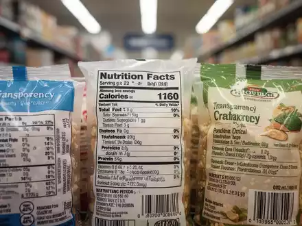 Nahaufnahme von Lebensmittelverpackungen mit Etiketten, die Nährwertangaben und Produktinformationen zeigen, im Hintergrund ein unscharfer Supermarktgang. - Foto: über boerse-global.de