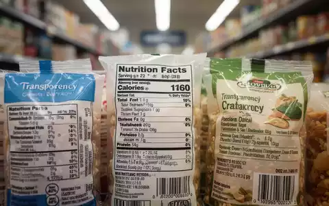 Nahaufnahme von Lebensmittelverpackungen mit Etiketten, die Nährwertangaben und Produktinformationen zeigen, im Hintergrund ein unscharfer Supermarktgang. - Foto: über boerse-global.de