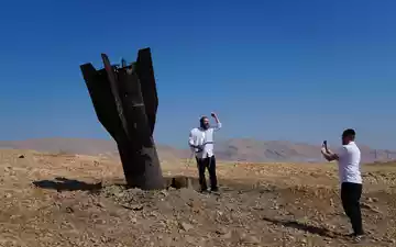 Menschen neben dem Wrack einer iranischen Rakete, die im Westjordanland eingeschlagen ist. - Foto: Mahmoud Illean/AP/dpa