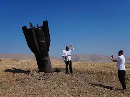 Menschen neben dem Wrack einer iranischen Rakete, die im Westjordanland eingeschlagen ist. - Foto: Mahmoud Illean/AP/dpa