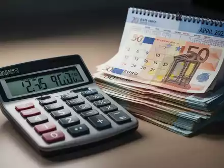 Ein Taschenrechner zeigt Finanzzahlen, daneben ein Stapel Euro-Banknoten und ein Kalender, der auf April 2025 geöffnet ist. - Foto: über boerse-global.de