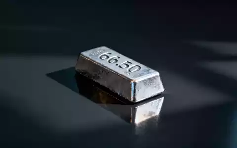 Ein einzelner Silberbarren mit eingraviertem '66.50' auf einer dunklen, reflektierenden Oberfläche, umgeben von Schatten. - Foto: über boerse-global.de