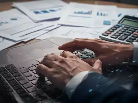 Eine Person tippt auf einem Laptop, umgeben von Finanzdokumenten und einem Taschenrechner, symbolisierend digitale Steuererklärung. - Foto: über boerse-global.de