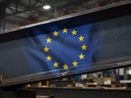 Nahaufnahme eines Stahlträgers mit einer Spiegelung der EU-Flagge, die Stärke und Schutz der europäischen Stahlindustrie symbolisiert. - Foto: über boerse-global.de