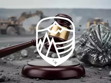 Ein Richterhammer schlägt auf einen Klangblock, im Hintergrund unscharf eine Mine oder Stibnit-Gestein. Symbolisiert einen Gerichtsentscheid, der den Bergbau stoppt. - Foto: über boerse-global.de