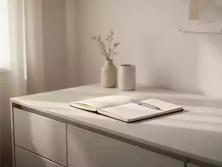 Ein aufgeräumter, minimalistischer Raum mit natürlichem Licht, das auf einen Schreibtisch fällt, auf dem ein Notizbuch liegt. - Foto: über boerse-global.de