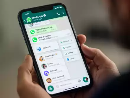 A smartphone screen showing WhatsApp chat filters and multi-account options, held by a person's hand. - Foto: über boerse-global.de