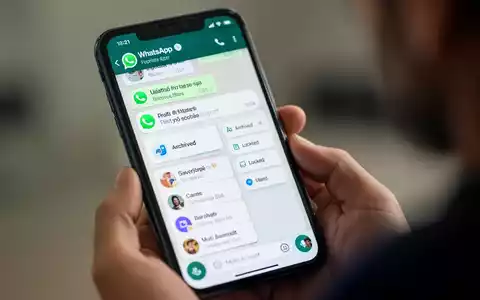A smartphone screen showing WhatsApp chat filters and multi-account options, held by a person's hand. - Foto: über boerse-global.de
