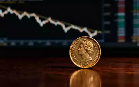 Eine einzelne, leicht abgenutzte schottische Pfundmünze auf einer dunklen Holzoberfläche, im Hintergrund eine verschwommene Finanzgrafik. - Foto: über boerse-global.de