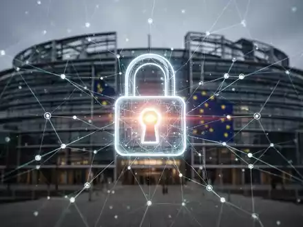 Ein stilisiertes, leuchtendes Vorhängeschloss-Symbol über einem digitalen Netzwerk mit dem Gebäude des Europäischen Parlaments im Hintergrund. - Foto: über boerse-global.de