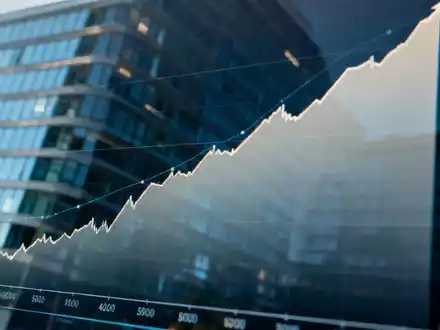 Eine Nahaufnahme eines Finanzdiagramms auf einem Bildschirm mit einem Aufwärtstrend und einer Spiegelung eines modernen Bürogebäudes. - Foto: über boerse-global.de