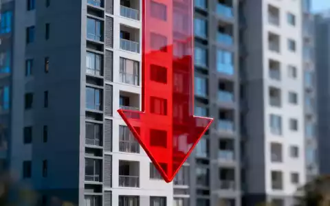 Ein modernes Wohngebäude mit einem großen, roten, nach unten zeigenden Pfeil davor, der einen Rückgang symbolisiert. - Foto: über boerse-global.de