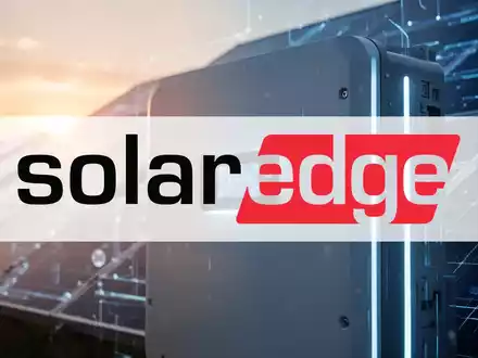 Nahaufnahme eines modernen Solarwechselrichters mit einem subtilen Glanz vor einem verschwommenen Solarpanel-Feld bei Sonnenaufgang. - Foto: über boerse-global.de