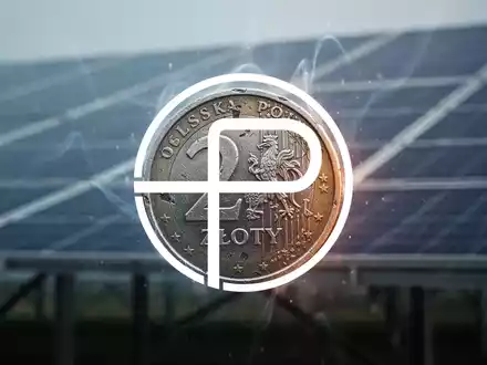 Eine einzelne, leicht beschädigte polnische Z?oty-Münze mit einem unscharfen Solarpanel-Feld im Hintergrund, das finanzielle Unsicherheit symbolisiert. - Foto: über boerse-global.de