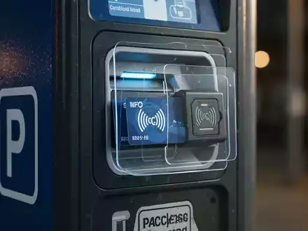 Nahaufnahme eines Parkautomaten mit einem manipulierten NFC-Kartenlesegerät, das auf eine Betrugsmasche hindeutet. - Foto: über boerse-global.de