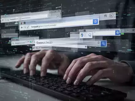 Ein Computerbildschirm zeigt fragmentierte Browserfenster und Suchleisten mit digitalem Code, Hände schweben über der Tastatur. - Foto: über boerse-global.de