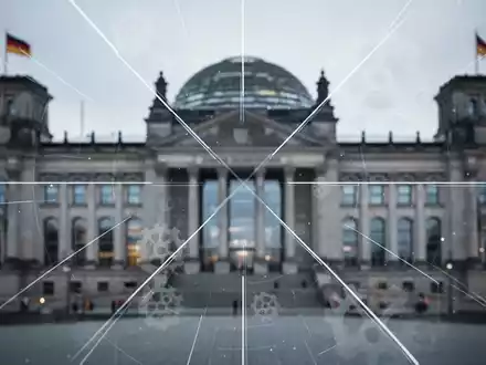 Eine stilisierte, unscharfe Darstellung des Reichstagsgebäudes mit überlagerten Linien und Zahnrädern, die Reform und Verhandlung symbolisieren. - Foto: über boerse-global.de