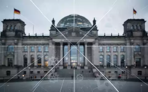 Eine stilisierte, unscharfe Darstellung des Reichstagsgebäudes mit überlagerten Linien und Zahnrädern, die Reform und Verhandlung symbolisieren. - Foto: über boerse-global.de