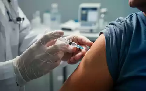 Eine Nahaufnahme zeigt die Hände eines Arztes, der einem Patienten eine Impfung verabreicht, mit Fokus auf Nadel und Arm. - Foto: über boerse-global.de
