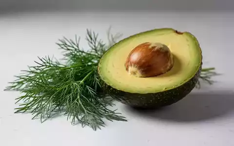 Eine aufgeschnittene Avocadohälfte und frische Dillzweige liegen auf einer hellen Oberfläche. - Foto: über boerse-global.de