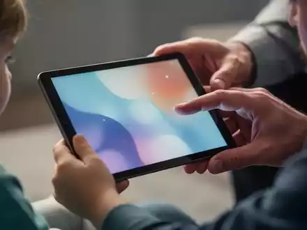 A child's hand holding a tablet with a blurred image, a parent's hand gently guiding it. Illustrates child safety and parental controls. - Foto: über boerse-global.de