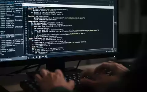 Close-up of a computer screen showing code in a command prompt, with hands typing on a keyboard blurred in the foreground. - Foto: über boerse-global.de