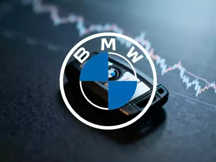 Ein BMW-Autoschlüssel auf dunklem Untergrund, im Hintergrund verschwommen ein fallender Börsenchart. Symbolisiert das 52-Wochen-Tief der Aktie. - Foto: über boerse-global.de