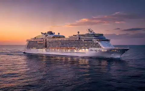 Ein luxuriöses Kreuzfahrtschiff, 'Mein Schiff Flow', segelt bei Sonnenuntergang auf einem ruhigen blauen Meer. - Foto: über boerse-global.de