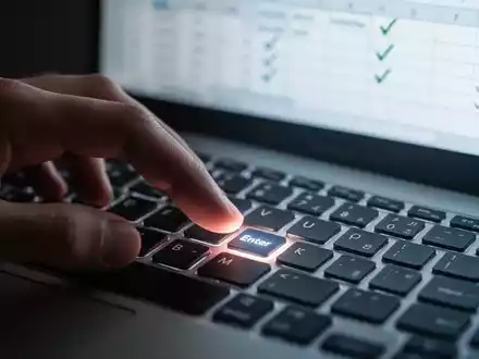 A hand over a computer keyboard, with a spreadsheet on screen showing checkmarks, illustrating Excel data entry. - Foto: über boerse-global.de