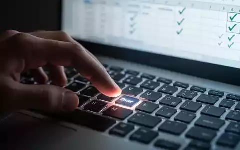 A hand over a computer keyboard, with a spreadsheet on screen showing checkmarks, illustrating Excel data entry. - Foto: über boerse-global.de