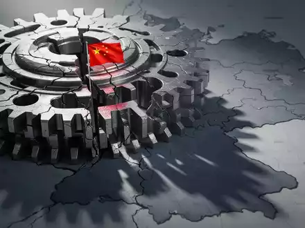 Ein großes, komplexes Industriezahnrad aus Seltenerdmetallen, das Risse aufweist, mit einer chinesischen Flagge, die einen Schatten auf eine Karte Deutschlands wirft. - Foto: über boerse-global.de