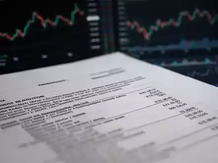 Ein Nahaufnahme eines juristischen Dokuments oder einer Finanzaufstellung mit unscharfem Text im Vordergrund und angedeuteten Börsencharts im Hintergrund. - Foto: über boerse-global.de