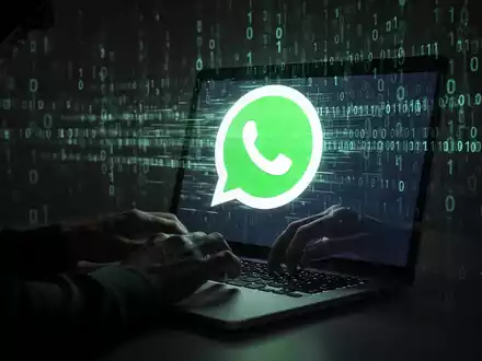 Shadowy hands typing on a laptop with a distorted WhatsApp logo on screen, binary code in background, symbolizing cyber espionage. - Foto: über boerse-global.de