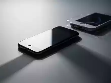 A new, brightly lit smartphone overshadows a blurred, older model, symbolizing Apple's shift from classic iPhones to AI-focused devices. - Foto: über boerse-global.de