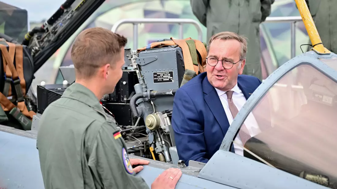 Ein Bundeswehr-Soldat zeigt dem Minister auf der ILA einen Tornado-Simulator.  - Bild: Sebastian Gollnow/dpa