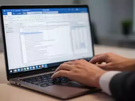 Hands typing on a laptop keyboard, with blurred Microsoft Word and Excel interfaces on the screen. - Foto: über boerse-global.de