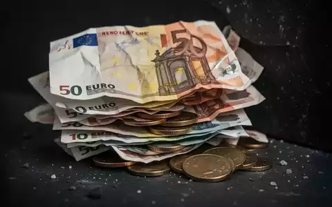 Ein Nahaufnahme-Bild von zerknüllten deutschen Euro-Banknoten und Münzen, die auf einer dunklen Oberfläche liegen und finanzielle Not andeuten. - Foto: über boerse-global.de