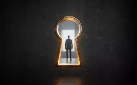 Ein stilisiertes, leuchtendes Schlüsselloch in einer dunklen Wand mit einer Personensilhouette in der Ferne, das Transparenz symbolisiert. - Foto: über boerse-global.de