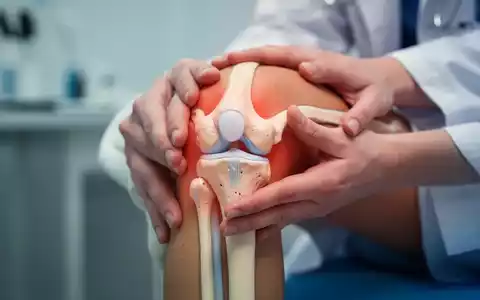 Hände halten sanft ein Kniegelenkmodell, im Hintergrund verschwommen medizinische oder therapeutische Elemente. - Foto: über boerse-global.de
