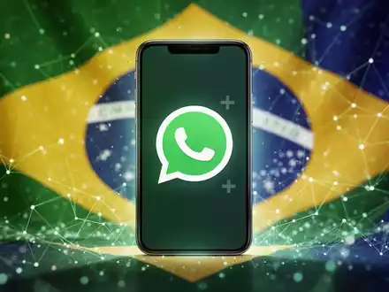 A smartphone screen showing the WhatsApp logo with a 'plus' symbol, set against a colorful, abstract background suggesting Brazil. - Foto: über boerse-global.de